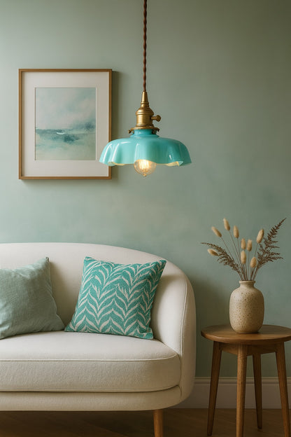 Lampe Avara en verre turquoise allumée dans un salon vert d’eau, suspension vintage au charme rétro élégant.