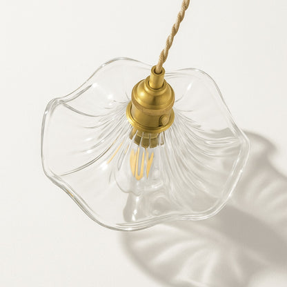 Vue plongeante sur une suspension en verre ondulé transparent avec douille dorée et ampoule LED décorative.