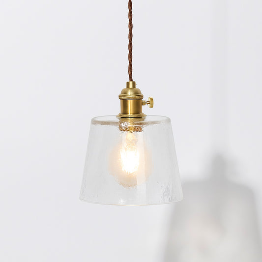 Suspension en verre transparent texturé avec douille laiton doré et cordon textile marron, style vintage.