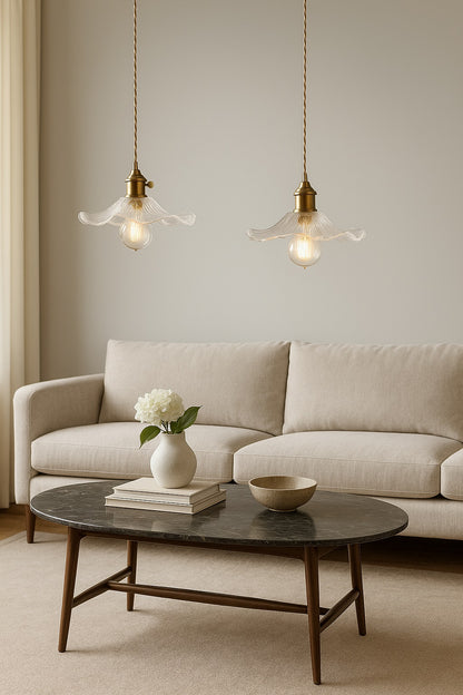Deux suspensions en verre soufflé au-dessus d’un salon élégant avec canapé beige et table basse en bois et marbre noir.