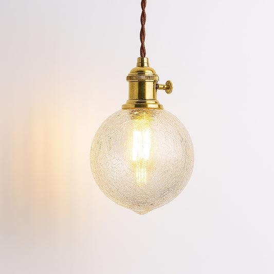 Suspension en verre transparent à facettes avec douille laiton doré et câble torsadé, style vintage industriel.