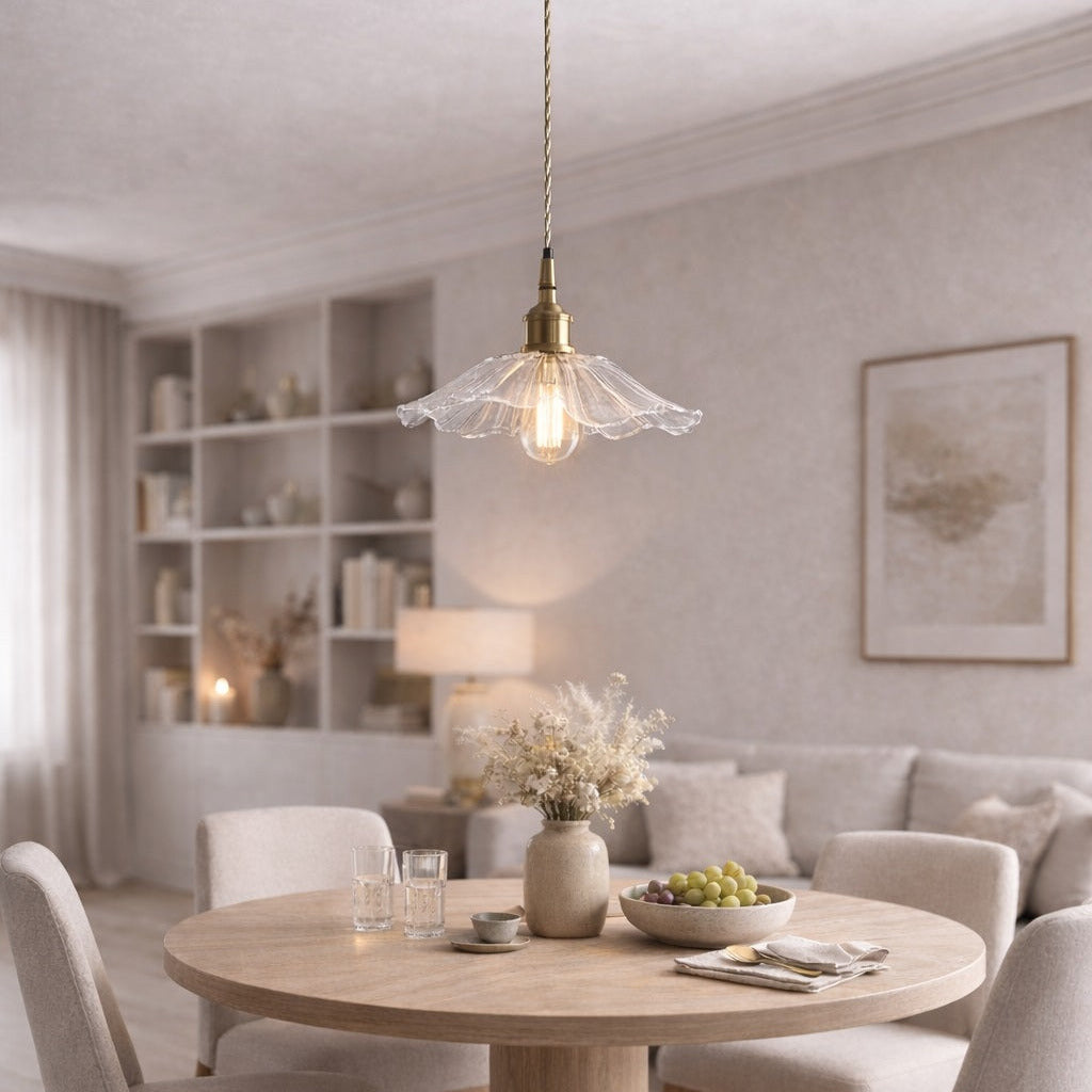Abat-jour suspension en verre transparent et laiton au-dessus d’une table ronde en bois dans un séjour lumineux