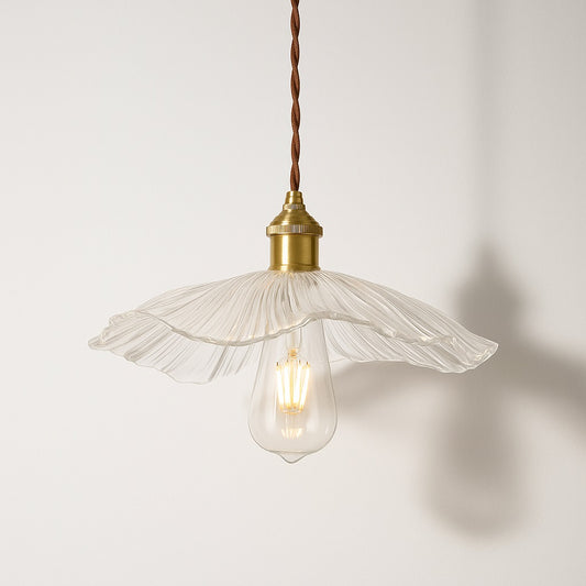 Suspension en verre transparent nervuré, forme pétale ondulé, douille laiton doré, lumière douce et organique.