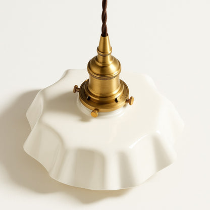 Vue plongeante d’un abat-jour en céramique blanche plissée avec douille dorée, suspension design style vintage.