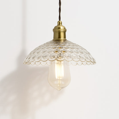 Suspension en verre transparent à reliefs ronds, bord festonné, douille laiton doré, design élégant et rétro.