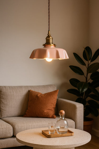 Lampe suspendue abat-jour rose allumée, ambiance chaleureuse de salon avec coussins bruns et plante verte