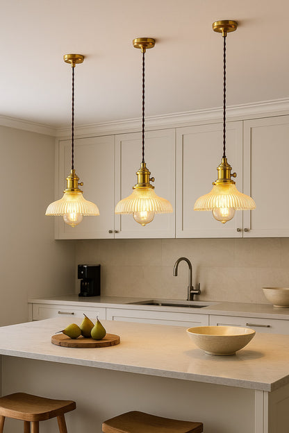 Suspensions abat-jour en verre ondulé doré illuminant une cuisine design avec lumière chaleureuse.