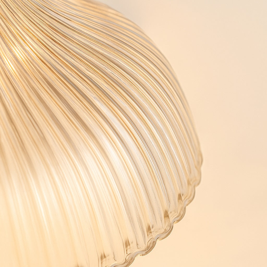 Gros plan sur un abat-jour en verre nervuré, texture détaillée et lumière naturelle douce des suspensions.
