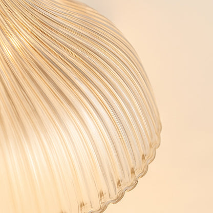 Gros plan sur un abat-jour en verre nervuré, texture détaillée et lumière naturelle douce des suspensions.