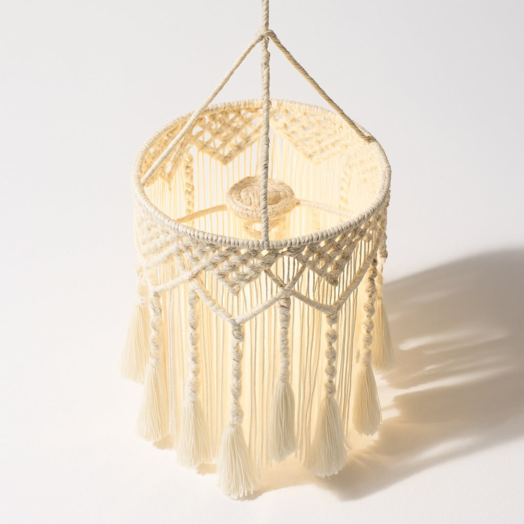 Abat-jour suspension en coton blanc tressé, détails macramé et franges, vue en angle sur fond blanc avec ombre portée.