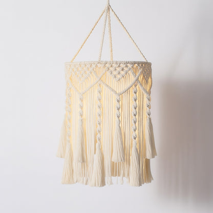 Suspension coton blanc tressé avec franges longues, motifs macramé et lumière chaude pour une lampe décorative bohème.