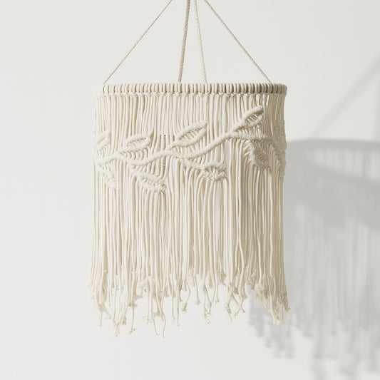 Suspension macramé blanche en coton tressé avec franges, installée au plafond et diffusant une lumière chaude et douce.