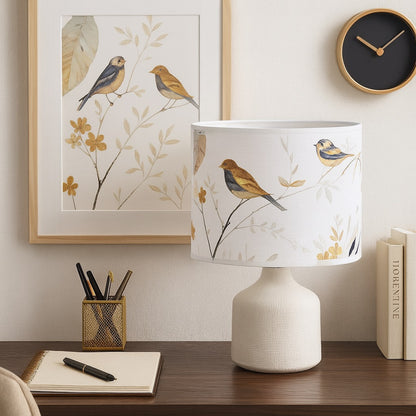 Abat-jour décoratif à motif d’oiseaux dorés sur fond blanc, lampe posée sur un bureau élégant au style nature.