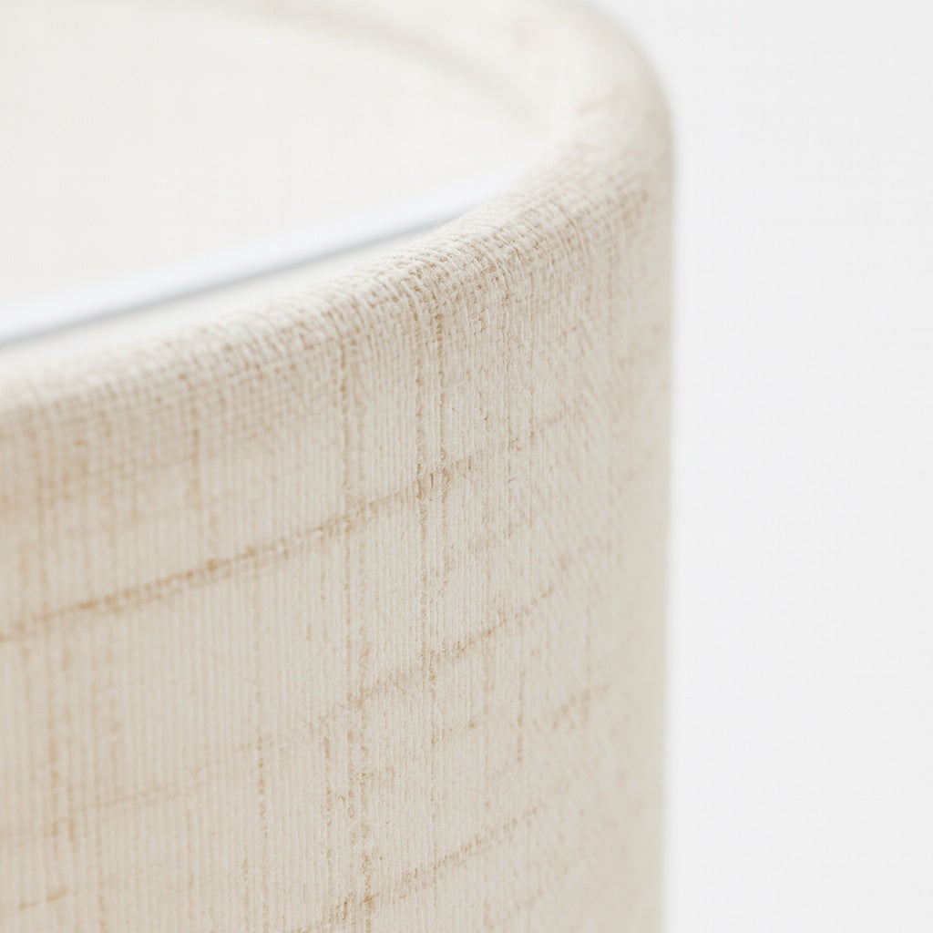 Abat-jour écru texturé avec reliefs linéaires, gros plan sur la matière pour montrer le style naturel et artisanal.