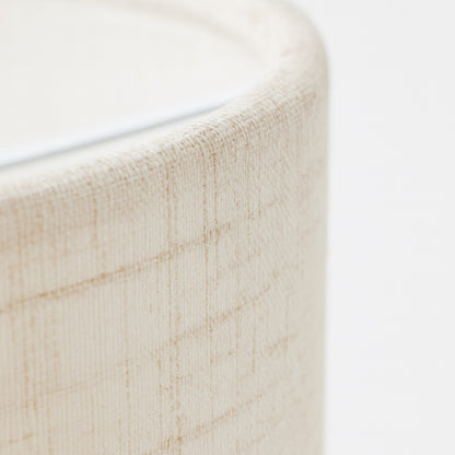 Abat-jour écru texturé avec reliefs linéaires, gros plan sur la matière pour montrer le style naturel et artisanal.