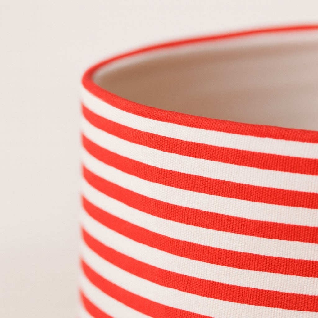 Gros plan sur un abat-jour rayé rouge et blanc, texture tissu détaillée pour lampe ou lampadaire design.