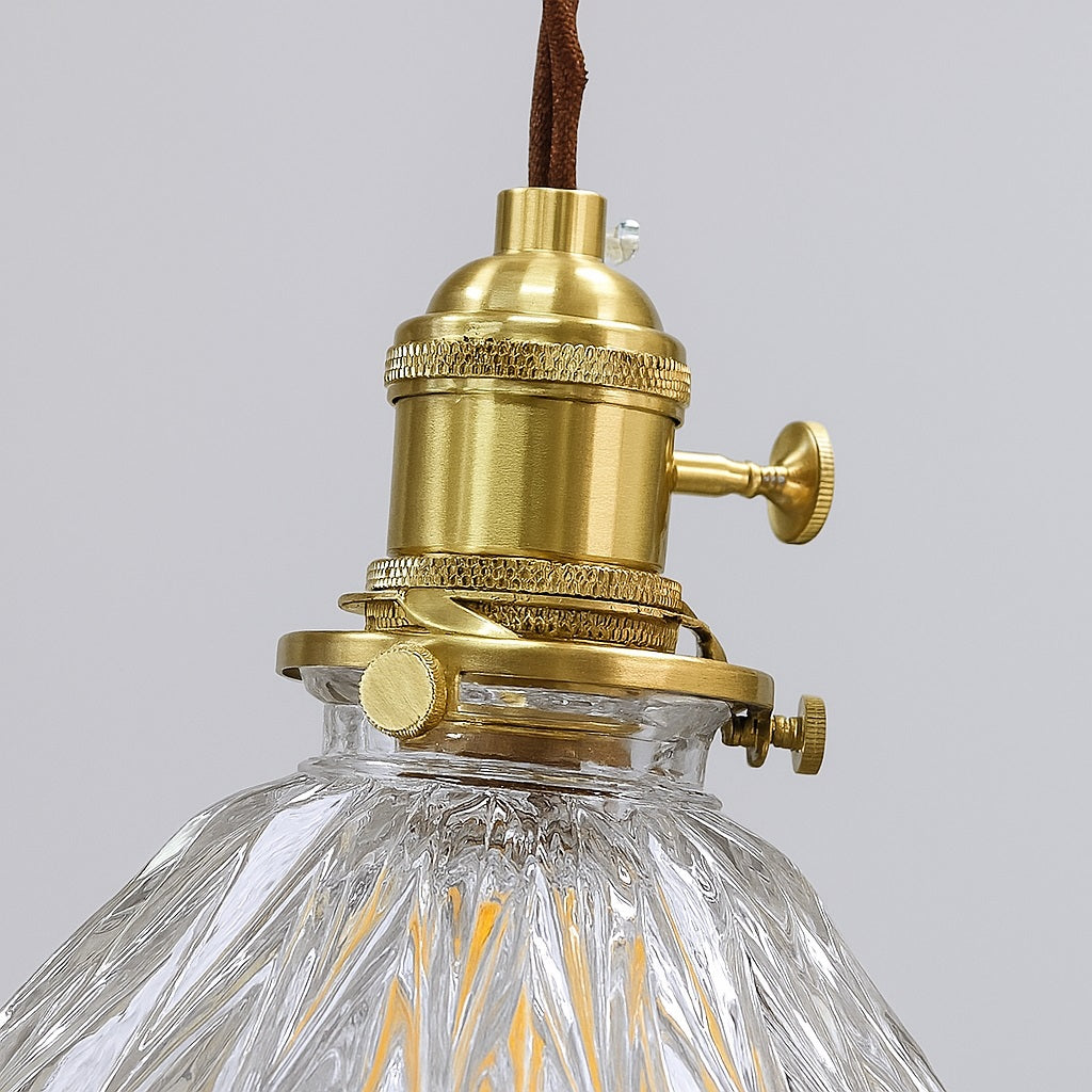 Détail d’un abat-jour en verre strié avec douille en laiton doré, finition haut de gamme pour une suspension vintage élégante.