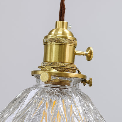 Détail d’un abat-jour en verre strié avec douille en laiton doré, finition haut de gamme pour une suspension vintage élégante.